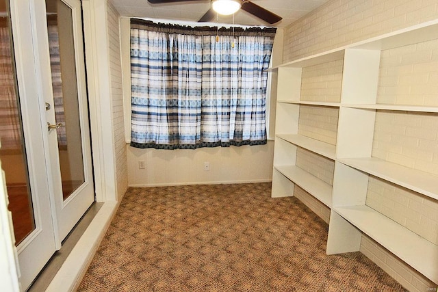 carpeted spare room featuring ceiling fan and brick wall