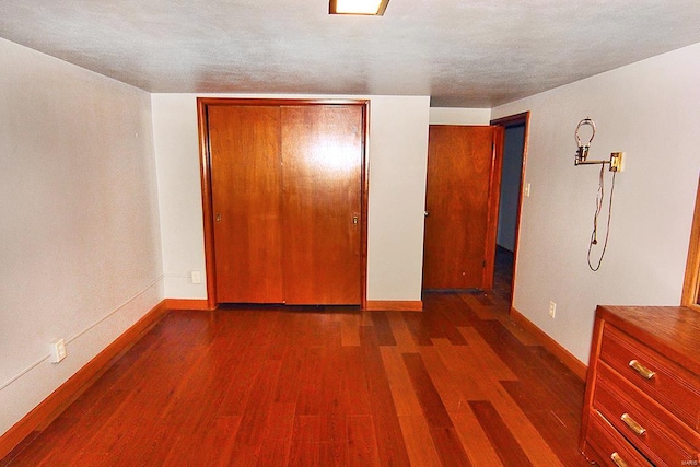 unfurnished bedroom with dark hardwood / wood-style floors, a textured ceiling, and a closet