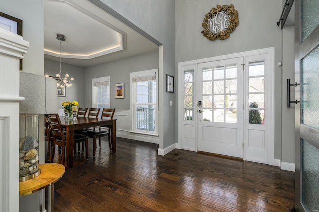 foyer entrance with a chandelier, dark hardwood / wood-style flooring, and a raised ceiling