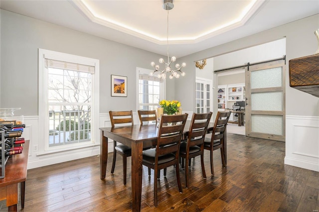 dining room with crown molding, a barn door, dark hardwood / wood-style flooring, and a tray ceiling