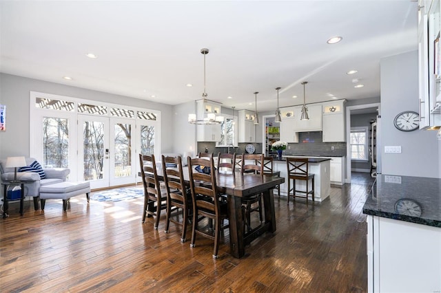 dining space featuring dark hardwood / wood-style flooring, french doors, and an inviting chandelier