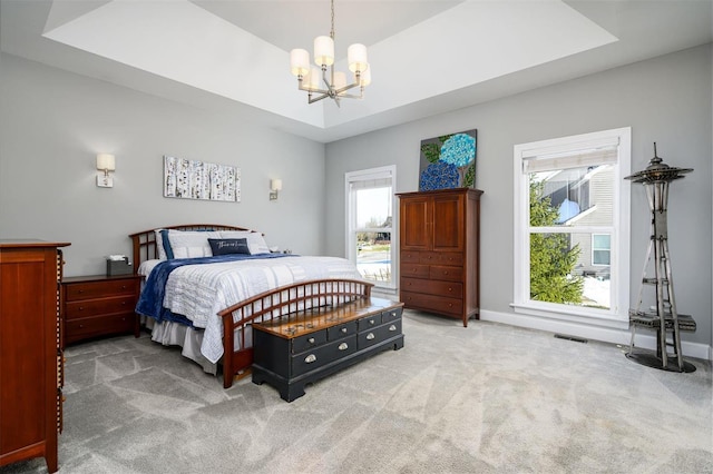 carpeted bedroom featuring a raised ceiling and a chandelier