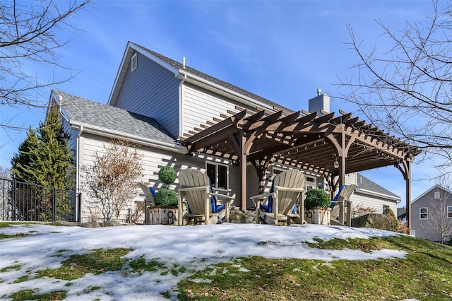 snow covered rear of property with a pergola