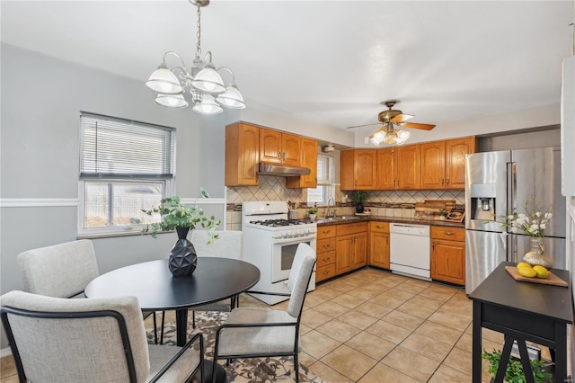 kitchen with tasteful backsplash, white appliances, sink, hanging light fixtures, and light tile patterned flooring