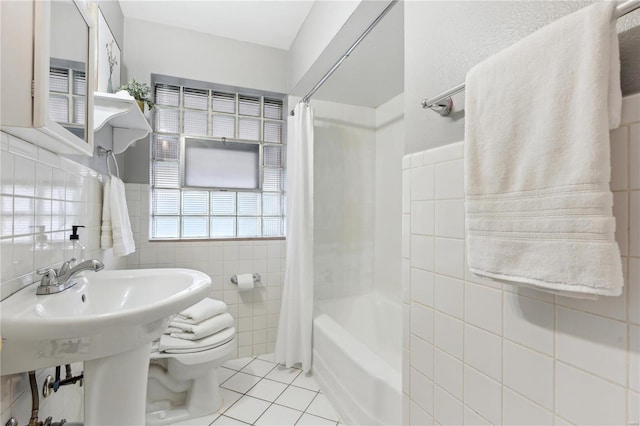 bathroom with tile patterned flooring, toilet, shower / bathtub combination with curtain, and tile walls