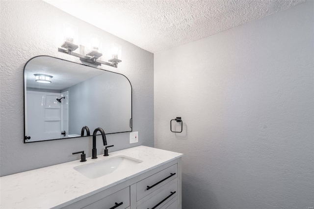 bathroom with vanity, a textured ceiling, and walk in shower