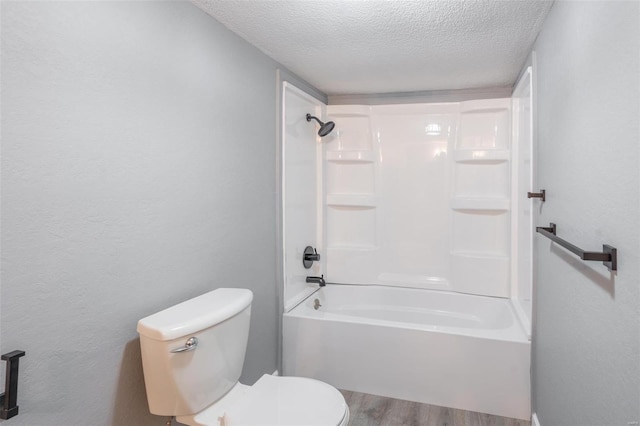 bathroom featuring hardwood / wood-style flooring, toilet, shower / tub combination, and a textured ceiling