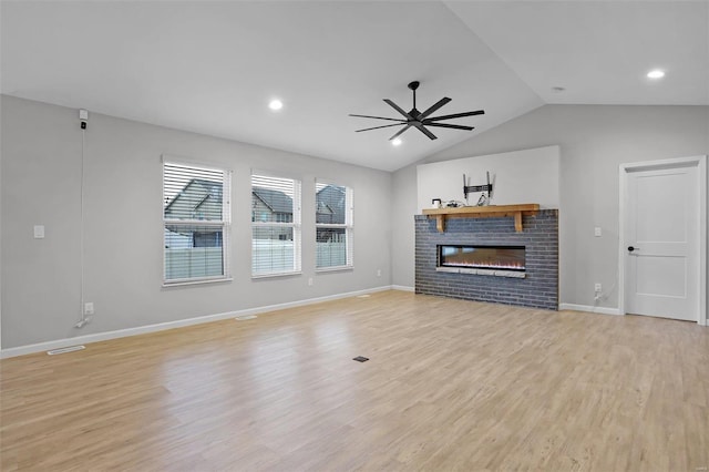 unfurnished living room featuring ceiling fan, a fireplace, lofted ceiling, and light hardwood / wood-style flooring