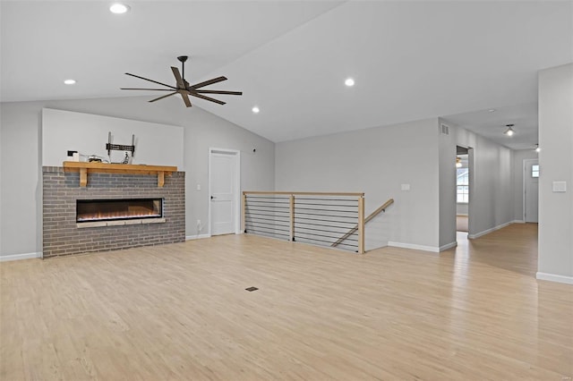 unfurnished living room featuring ceiling fan, a fireplace, lofted ceiling, and light hardwood / wood-style flooring