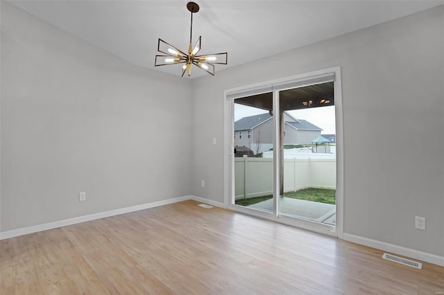 empty room featuring a chandelier and light hardwood / wood-style floors