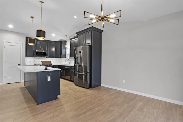 kitchen with a center island, lofted ceiling, hanging light fixtures, light wood-type flooring, and appliances with stainless steel finishes