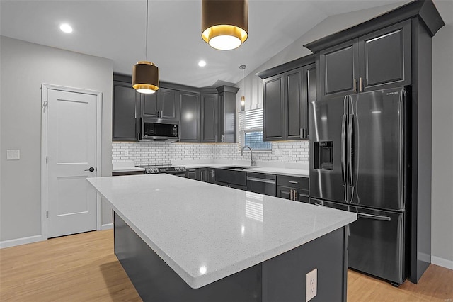 kitchen with pendant lighting, stainless steel appliances, a kitchen island, and lofted ceiling