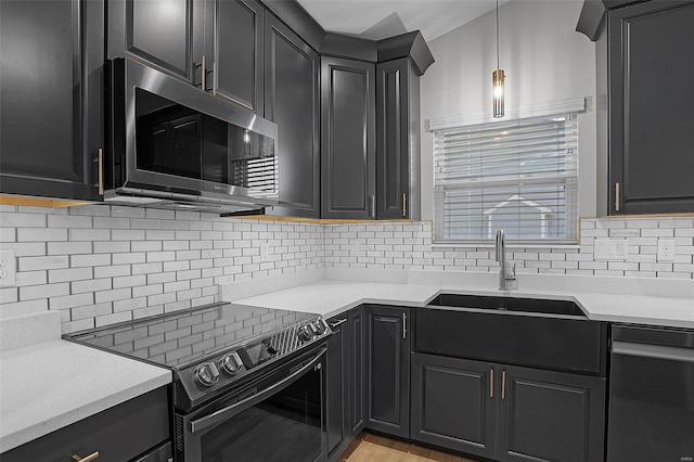 kitchen with pendant lighting, decorative backsplash, sink, and stainless steel appliances