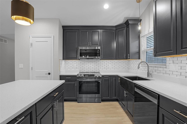 kitchen featuring backsplash, stainless steel appliances, light hardwood / wood-style flooring, and hanging light fixtures