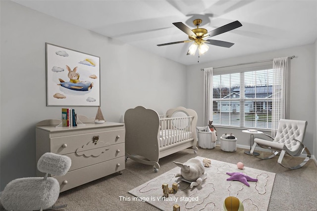 carpeted bedroom featuring ceiling fan and a crib