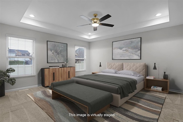 bedroom featuring ceiling fan, a raised ceiling, and light colored carpet