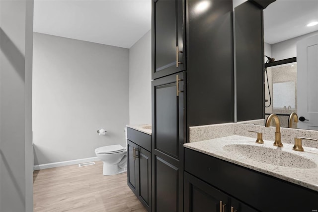 bathroom featuring vanity, toilet, wood-type flooring, and a shower with shower door