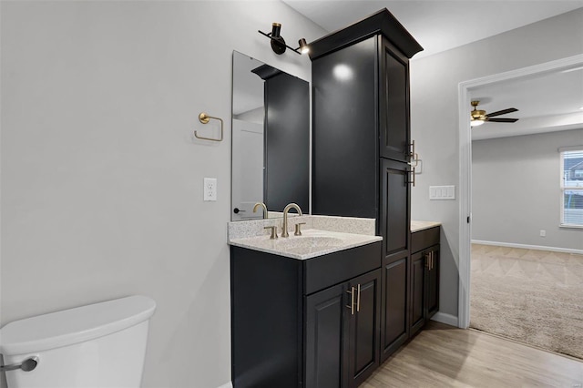 bathroom with ceiling fan, toilet, wood-type flooring, and vanity