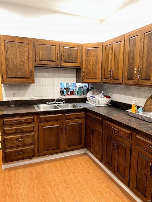 kitchen with sink, decorative backsplash, and light hardwood / wood-style flooring