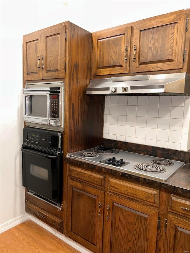 kitchen featuring tasteful backsplash, electric cooktop, black oven, and light hardwood / wood-style flooring