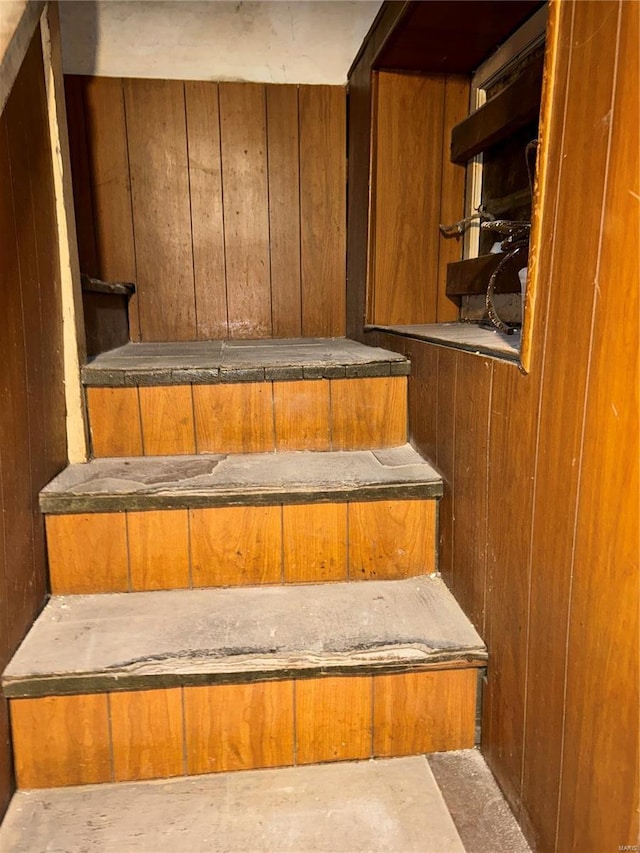 staircase featuring wood walls