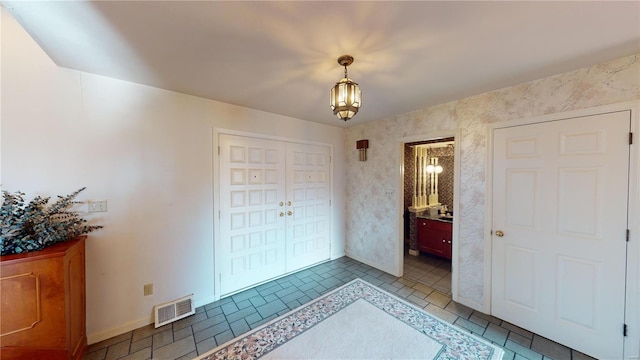 bedroom featuring an inviting chandelier, ensuite bath, and a closet