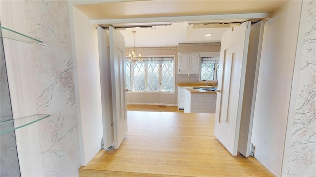 hallway featuring a chandelier and light hardwood / wood-style flooring