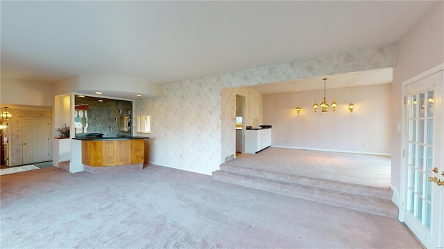 unfurnished living room with carpet floors and an inviting chandelier