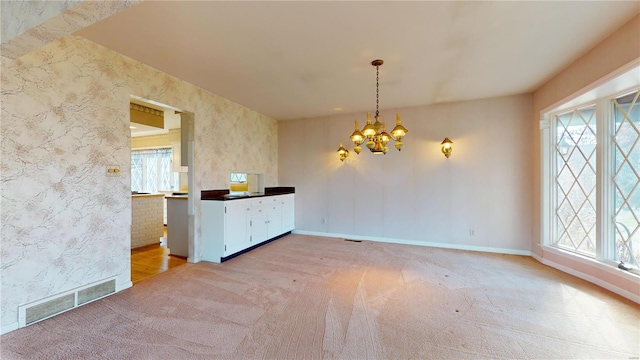 unfurnished dining area featuring plenty of natural light, light colored carpet, and an inviting chandelier