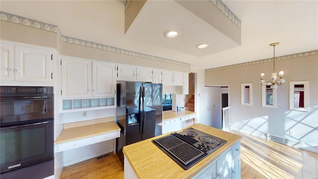 kitchen with light wood-type flooring, black appliances, pendant lighting, a notable chandelier, and white cabinetry