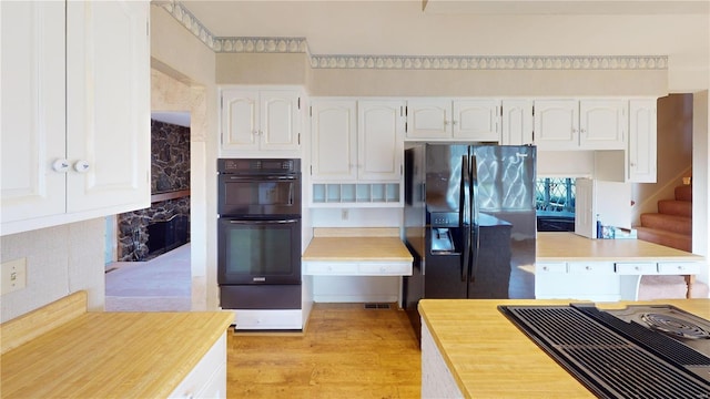 kitchen with white cabinets, black appliances, and light wood-type flooring