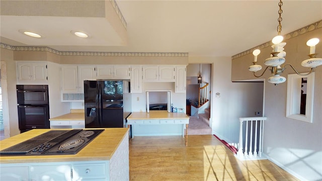 kitchen with a center island, hanging light fixtures, white cabinets, and black appliances