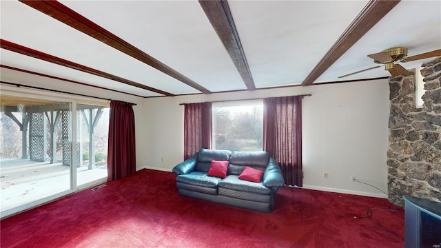 living area featuring beam ceiling, ceiling fan, plenty of natural light, and carpet