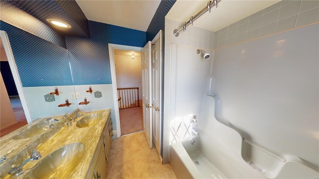 bathroom with tiled shower / bath combo, tile walls, and vanity