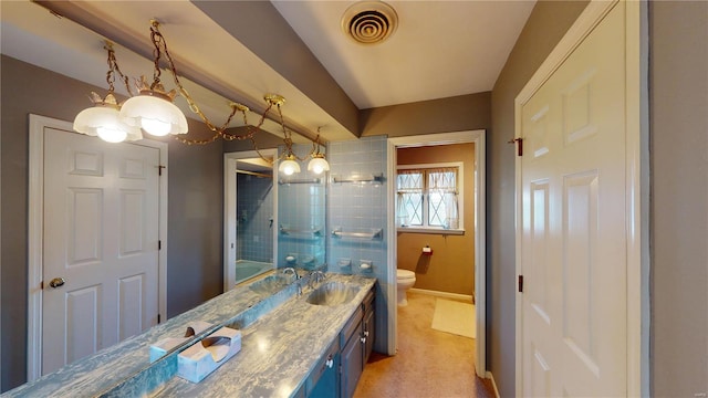 bathroom featuring a tile shower, vanity, toilet, and a notable chandelier