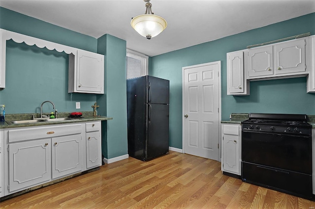 kitchen with light wood-type flooring, sink, black appliances, pendant lighting, and white cabinets