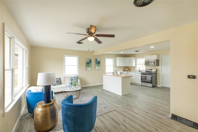 sitting room with ceiling fan, light wood-type flooring, and sink