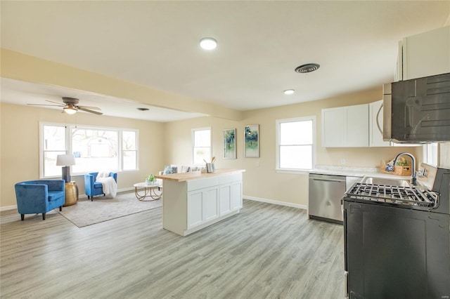 kitchen with stainless steel appliances, white cabinetry, plenty of natural light, and light hardwood / wood-style floors