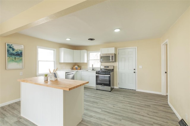 kitchen with a wealth of natural light, white cabinetry, and stainless steel appliances