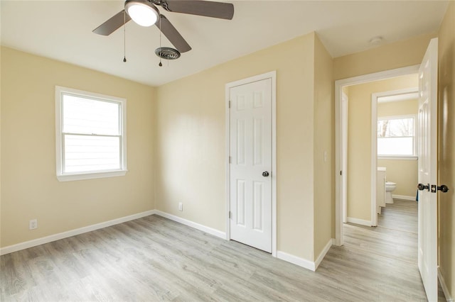 unfurnished bedroom featuring ceiling fan, light wood-type flooring, ensuite bathroom, and a closet