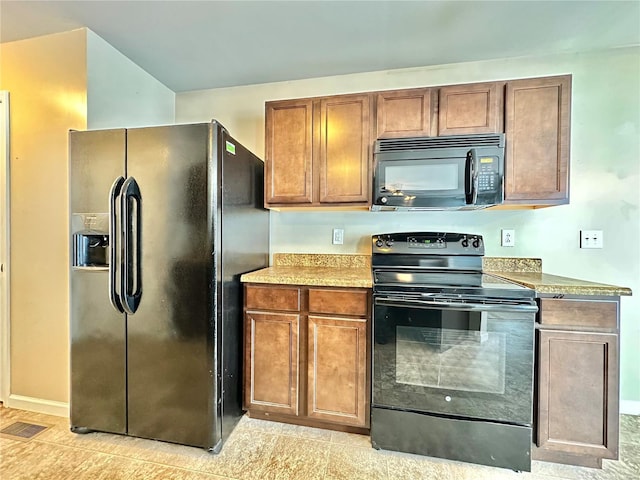 kitchen with black appliances and light tile patterned flooring