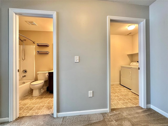 bathroom with washer and clothes dryer, shower / bathtub combination, and toilet