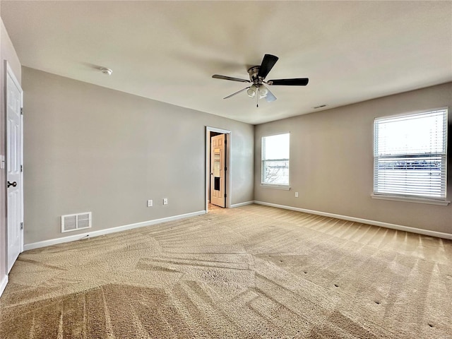 unfurnished bedroom with light carpet, multiple windows, and ceiling fan