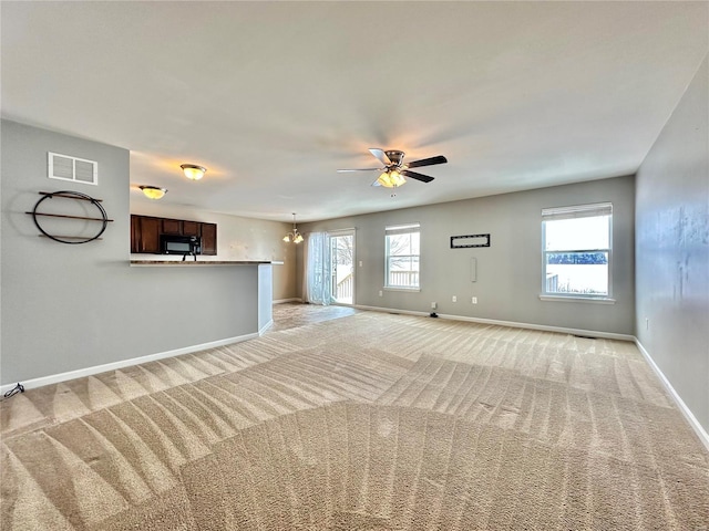 unfurnished living room with ceiling fan with notable chandelier and light carpet