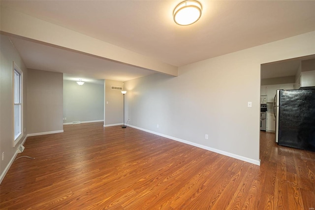 unfurnished room featuring hardwood / wood-style flooring and beamed ceiling