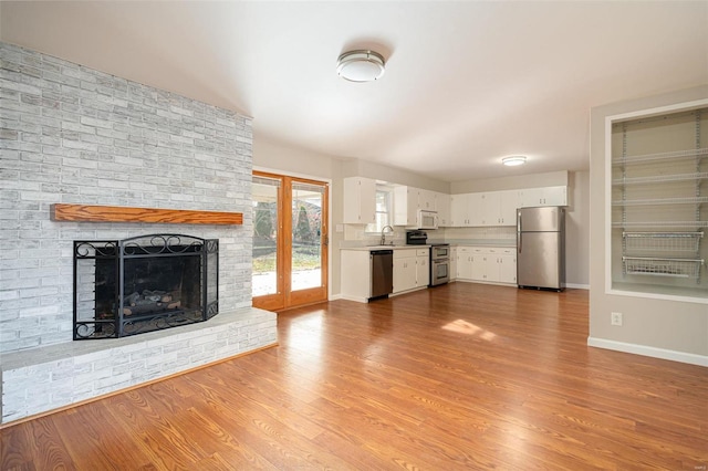 unfurnished living room featuring a fireplace, sink, and light hardwood / wood-style flooring