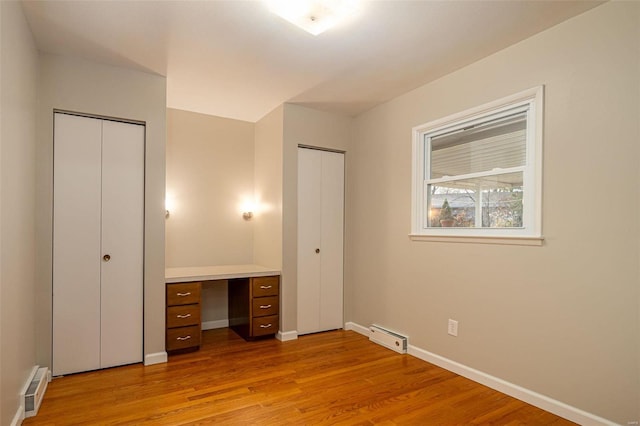 unfurnished bedroom with multiple closets and light wood-type flooring