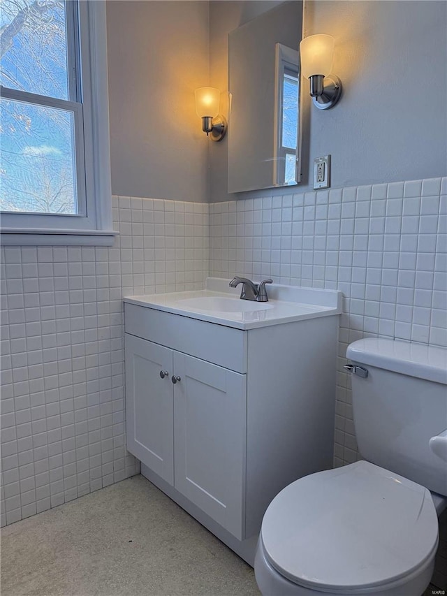 bathroom with tile walls, vanity, and toilet