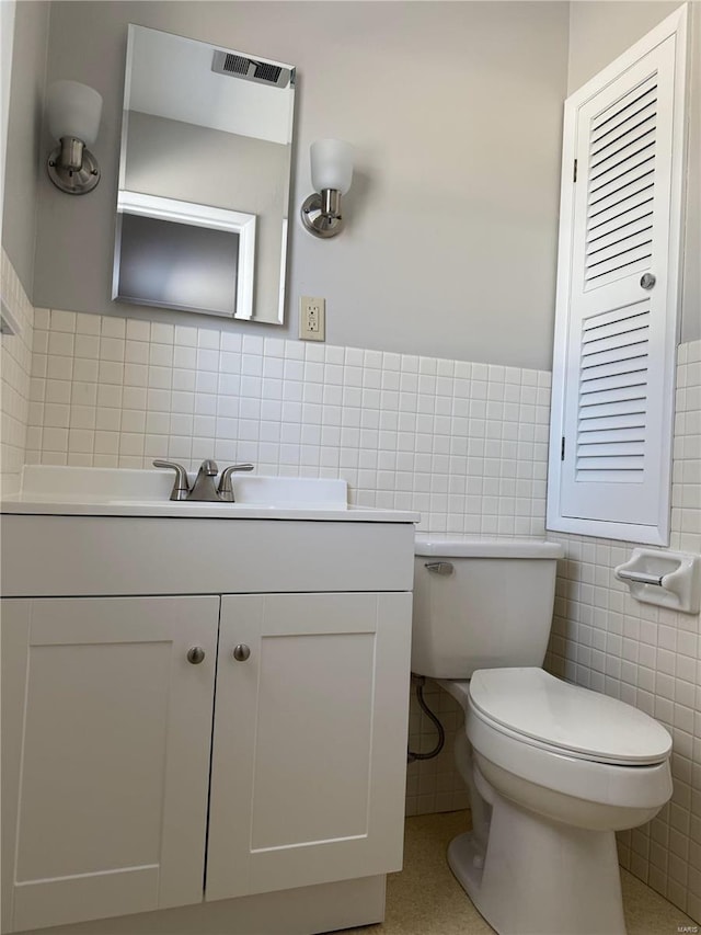 bathroom featuring vanity, toilet, and tile walls