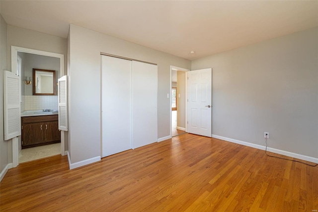 unfurnished bedroom with a closet, sink, and light hardwood / wood-style flooring